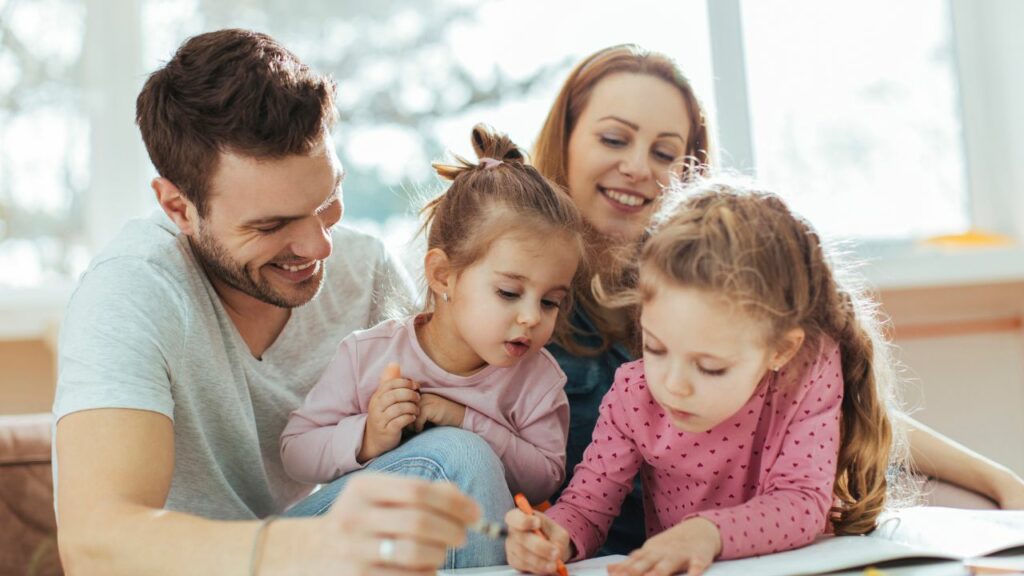 Two parents watching their child write at a table